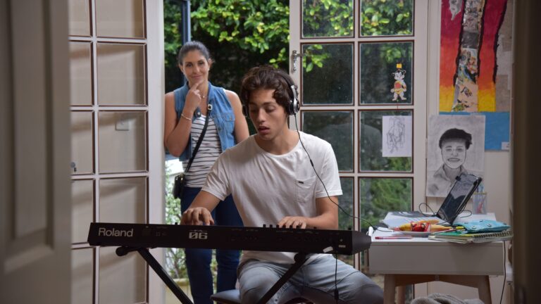 Mother watches son as he plays piano