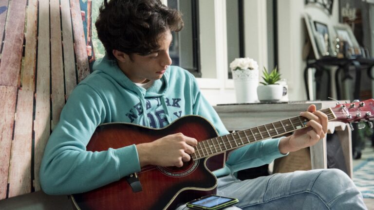 Teenage boy practices guitar